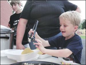 Andy Lenhart, 7, shows his mom Debbie how high a mountain of shredded cheese he can put on his taco at the tailgate party in the back playground at Wayne Trail Elementary School in Maumee. Afterward, participants walked to the Maumee High School football field to watch the Panthers  game against Bowsher.