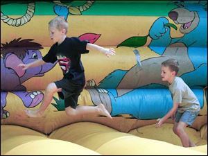 Grant Donald, 7, and his brother Drew, 6, from left scramble on one of the inflated amusement areas.