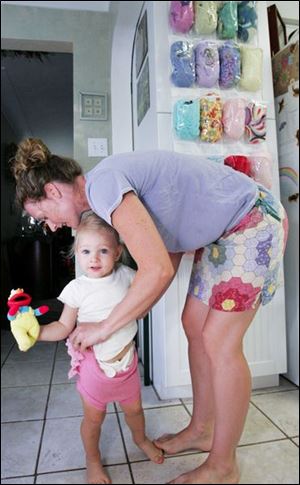 Shelly De Meo checks her daughter Sage's diaper cover. Behind are the various diaper covers the family has for Sage.
