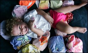Sage Colon, 2, is comfortable surrounded by some of her cloth diapers and diaper covers.
