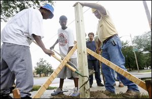 Working in the CITE program, Nate Lee, left, and DaSHAWN Jones help install a fence for the community garden at TenEyck Tower with help from mentor Brian Haley. Looking on at rear is Brian Zelip, supervisor with Toledo Grows.