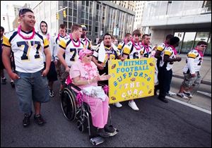 Members of the Whitmer High School football team push Candace Meridieth of West Toledo. Ms. Meridieth was diagnosed with cancer last spring and covered the 3.1-mile course in a wheelchair.