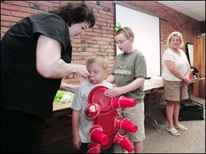 Lynda McKinney of Oregon and in hula outfit, checks on the progress of "a bunch of grapes", a costume made with balloons and safety pins.