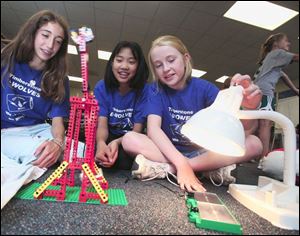 Elizabeth Sares, Michelle Li, and Jordan Truitt, all 12, work on a solar-powered toy at Sylvania's Timberstone Junior High as part of an energy-conservation awareness project.