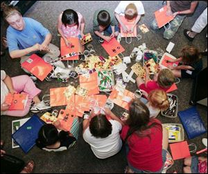 Participants decorate trick-or-treat bags with bags and materials supplied by the library.