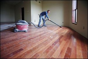 Jeremy Stotz, an employee of owner and developer Ken Wickenheiser, vacuums dust off of hard wood floors in a room at the historic City Hotel in downtown Monroe.