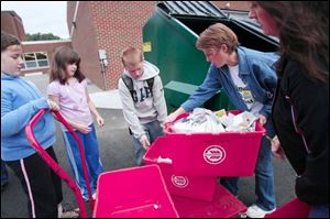 Victoria Riley, left, Kimberly Bertz, and Jordan Bopery help parent volunteers Joanna Kirchoff and Charlotte Slattery place recycled paper into the bin at Hill View Elementary. Students come to school early one day a week for the recycling project.