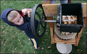 Logan Vargo, 3, turns the handle of an antique cider press to make apple juice.