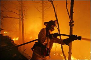 Wind-whipped flames silhouette a firefighter in Running Springs, Calif. Firefighters had conceded defeat in some areas.
