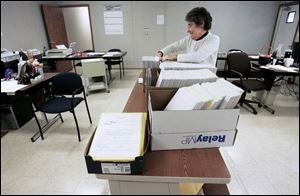 Hancock County Board of Elections clerk Donna Spitler sorts through more than 2,000 absentee ballots in the board's temporary headquarters. Last summer's flooding destroyed about 91 of the county's 300 voting machines. 