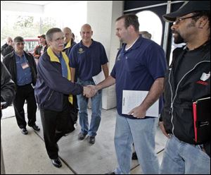  UAW President Ron Gettelfinger, left, shakes hands with a local union official as he arrives to discuss the contract.