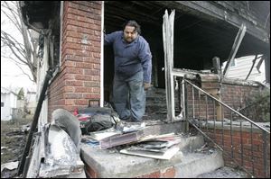 Anthony Diaz, the only person to survive a fire that killed four family members Wednesday, night, removes some items from the home at 4046 Lyman Ave. A candle started the fire.