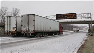 Trucks pass under a message board on westbound Interstate 80 indicating an ice storm warning near Des Moines, Iowa, on Saturday, Dec. 1, 2007.