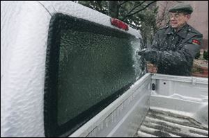 Tom Benecke, a Government Center security guard, scrapes a truck window in a chilly task necessitated by the storm.
