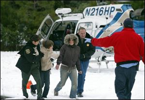 Joshua Dominguez, second from left, and Alexis Dominguez, third from left, are helped by authorities after they were flown by helicopter to Sterling City, Calif., after their rescue.