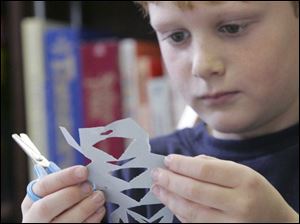 NBRN winter03p 2 12/28/2007   BLADE PHOTO/Lori King    Chad Pica, 8, of Luna Pier, makes a cut-out snowflake during Winter Wonderland Craft party at Rasey Memorial Branch Library in Luna Pier, Mich.