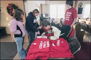 Maumee High School student Marissa Tanner, left, and her sister, Laureen Tanner, a graduate, buy a T-shirt supporting Maumee teachers from Nathaniel Mosher, who checks the paid list, and Phil Beasley at St. Timothy Lutheran Church in Maumee. 