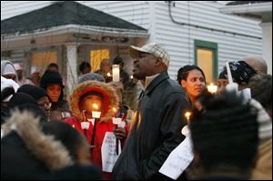 Pastor Arnold Manley, center in hat, of New Morning Star Missionary Baptist Church, leads crowd in song. Tarika Wilson's stepsister Tanea Wilson stands to his right. 
