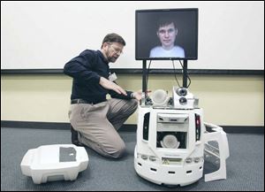 Ted Ronau, manager of technology development at the University of Toledo's Center for Creative Instruction, explains modifications he made to put a face on EMC. The robot helps recruit prospective students.