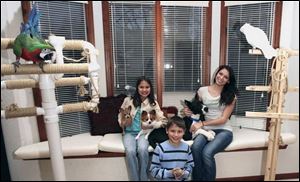 From left, the Cusick siblings, Emilie, Jordan, and Kristin, are seeking donations for the Toledo Area Humane Society. Jordan Cusick, above, has Rex the lizard in hand while Precious the dog and Silvey the bird look on. Sister Emilie, at right, shares the couch with Oscar, the family's Great Dane puppy.