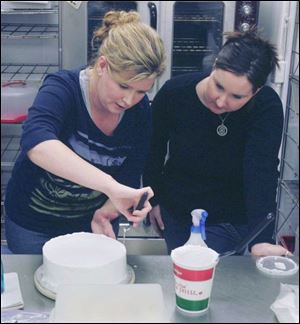 Cake Arts Supplies instructor Carey Cramer, left, shows Michelle Fielder how to frost a cake.