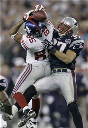 New York Giants receiver David Tyree (85) catches a 32-yard pass in the clutches of New England Patriots safety Rodney Harrison (37) during the fourth quarter.