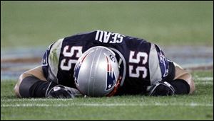 New England linebacker Junior Seau appears to be injured, but he is prostrate on the University of Phoenix turf because the Giants' Plaxico Burress has just scored the go-ahead touchdown.