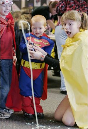 NBRN heroes07p  02/02/08  The Blade/Dave Zapotosky Caption: Travis Post, 5, of Dundee, Mich., dressed as Superman, fires a blast from a can of string with the help of Kia Edy, 13, of Temperance, Mich., right, during the Superheroes Training Camp at the Ida Branch Library in Ida, Mich., on Saturday, February 2, 2008. Looking on at left is Noah Dusseau, 5, of Temperance. Summary: Superheroes Training Camp at the Ida Branch Library in Ida, Mich.