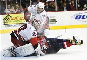 Washington's Alex Ovechkin slams into Carolina goaltender Cam Ward in a battle for the top spot last night in the Southeast Division. The Hurricanes won 2-1.