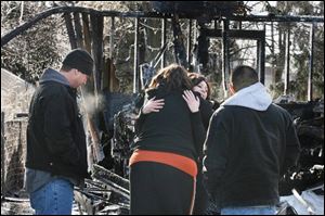Tracy Ulrich, center left, hugs Jamie Irwin while Scott Shepard, left, and Xavier Cardenas examine what's left of the ranch-style house. Mr. Cardenas and Ms. Irwin alerted the residents to the blaze and are credited with saving their lives.