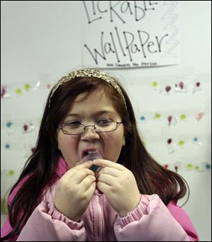 Slug: NBRN wonka21p  Date: 02/14/2008         The Blade/Andy Morrison       Location: Dundee       Caption: Marie Underwood, 7, Dundee, samples the lickable wallpaper at the Willy Wonka Chocolate Party at Dunee Branch Library, Thursday, 02/14/2008.         Summary: