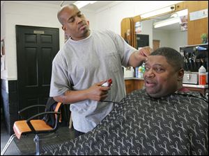 Barber Ray Oliver trims Keith Harris' hair at Tapers Barber Shop, a good place to catch up on local history.