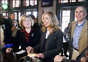 Chelsea Clinton signs a bun as Ohio Sen. Teresa Fedor, left, and Tony Packo, Jr. watch.