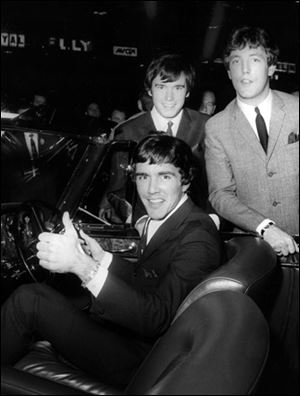Dave Clark, gives a thumb's up sitting in a Bentley Continental, with the other members of the band Dave Clark Five band, Dennis Payton and Mike Smith, right, at the International Motor Show at Earl's Court, in London, England, in this Oct. 19, 1965, file photo. Smith died from pneumonia Thursday, his agent said.