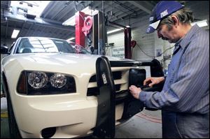 Bob Keel installs equipment on a police car at the fleet service station on Spielbusch Avenue.