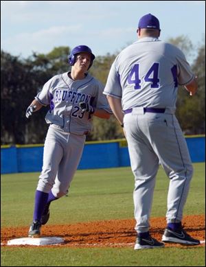 Bluffton University s Cody McPherson is congratulated by
coach James Grandey after hitting a home run during yesterday s opening game against Eastern Mennonite University.
