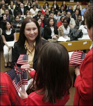 Kenya native Jacqueline Therese Busch receives her flag during the naturalization ceremony at the University of Toledo college of law where 81 immigrants became citizens.