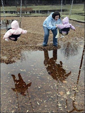 One-year-old Sophie Gibson, left, and her twin sister, Bailey, are reflected in the standing water beneath them as they are pushed on the swings at Wildwood Preserve
Metropark by their mother, Sara, of Toledo. The ground in northwest Ohio and elsewhere in the state has been
saturated by the near-record snowfall this winter, and forecasters are calling for rain this morning, Thursday, and Friday. 
