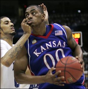 Darrell Arthur of Kansas takes it on the chin as he tries to slip past Memphis defender Shawn Taggart. Arthur led the Jayhawks on the night with 20 points and 10 rebounds.