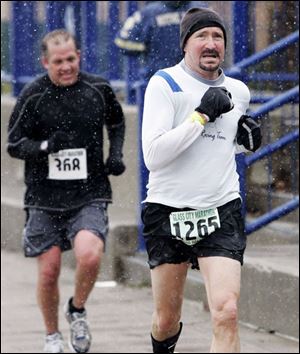 Jon Monheim of Perrysburg, left, and Dr. Jim Fanning of Medina, Ohio, blaze a path through snow as they near the finish line in downtown Toledo's Promenade Park for the 32nd annual Glass City Marathon. 