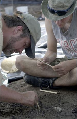 Brian Redmond, left, of the Cleveland Museum of Natural History brushes soil from artifacts at the site in 2004. 
