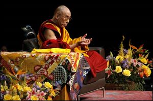 Wearing his traditional robe and sitting cross-legged, His Holiness the Dalai Lama talks to a sold-out crowd at Crisler Arena.