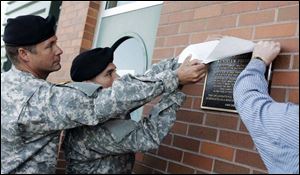 Unveiling a plaque memorializing Sgt. Kendell K.Frederick, above, are 1st Sgt. Douglas Wilson, left, and Staff Sgt. Edward Villareal. 
