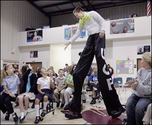 Blissfield, Mich., native Neil Sauter, on stilts, greets students at the New Bedford Academy in Lambertville, Mich. 