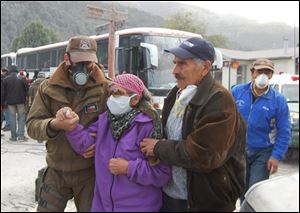 Residents wear protective masks as they evacuate the village of Futaleufu near the Chaiten volcano in southern Chile on Tuesday. The Chaiten volcano spewed incandescent material and blasted ash into the sky on Tuesday, prompting a total evacuation of the provincial capital and other settlements. (ASSOCIATED PRESS)
<br>
<img src=http://www.toledoblade.com/graphics/icons/video.gif> <b><font color=red>VIDEO</b></font color=red>: <a href=