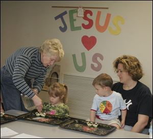 Lola Nelson, left, helps Ryan Nordahl with seeds as her brother, Jack, and mother, Linda Nordahl, observe.