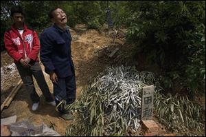 Bai Yushan, second from left, grieves near the branch-covered burial mound of his grandson Tian Chao who died after a school dormitory collapsed following Monday's quake in Muyu, southwestern China's Sichuan province, Sunday, May 18, 2008.