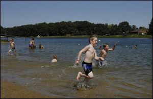 Children run and splash in the water while spending an afternoon at the beach at Olander Park in Sylvania.