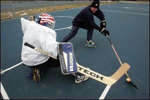 Jesse Decker tries to get  past the defense of goalie Tom Robertson during a practice session of the new Toledo Street Hockey Club.