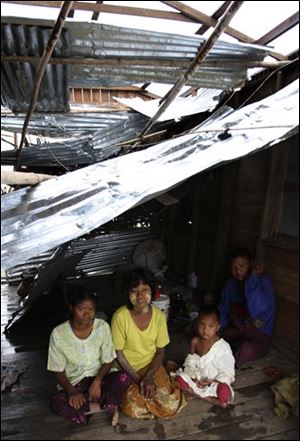 A Myanmar family live in a house which was destroyed by cyclone Nargis on the outskirts of Yangon, Myanmar, Sunday, May 18, 2008. Thousands of children in Myanmar will starve to death in two to three weeks unless food is rushed to them, an aid agency warned Sunday as an increasingly angry international community pleaded for approval to mount an all-out effort to help cyclone survivors. 